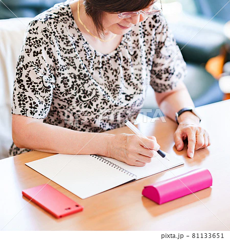 ノートに文字を書きながら脳活を行うシニア女性